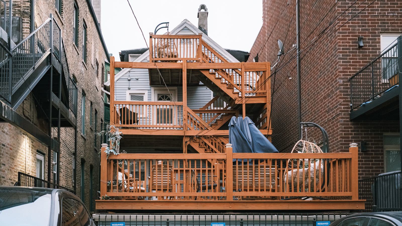 Multi-level wooden deck with stairs behind brick buildings